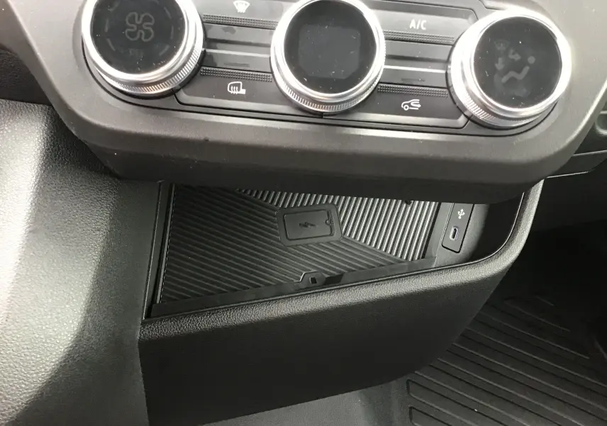 Vue rapprochée de la console centrale du Renault Master gris urbain 2025, montrant les commandes de climatisation et un chargeur smartphone sans fil.