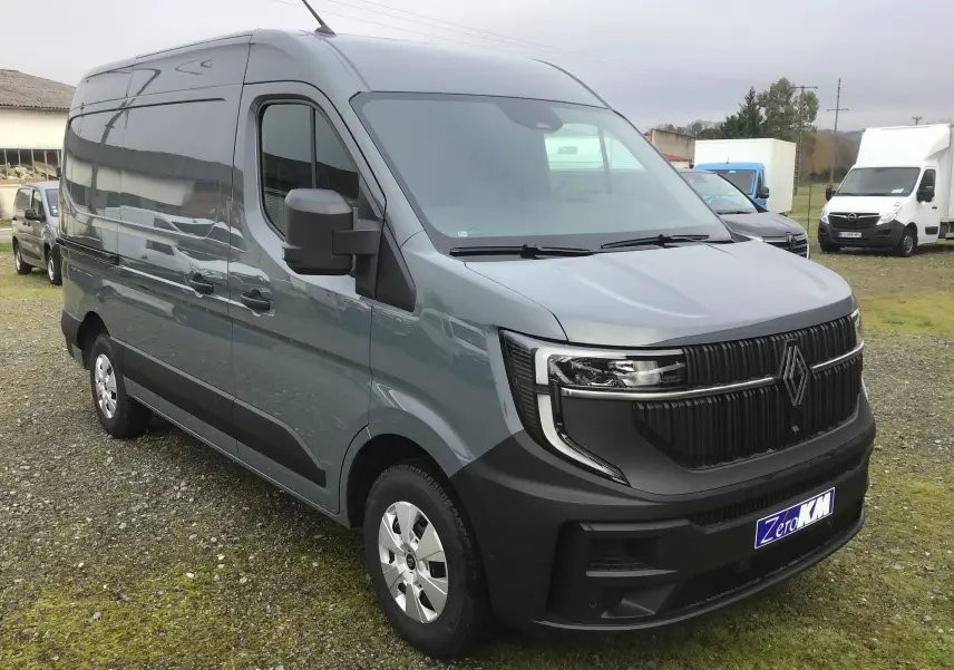 Vue 3/4 avant d’un Renault Master L2H2 gris urbain avec calandre noire et pare-chocs noir mat sur un terrain extérieur.