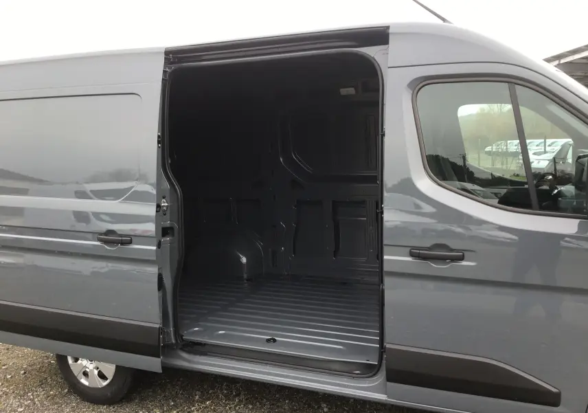 Vue latérale droite du Renault Master gris urbain 2025 avec porte coulissante ouverte montrant l’espace de chargement vide.