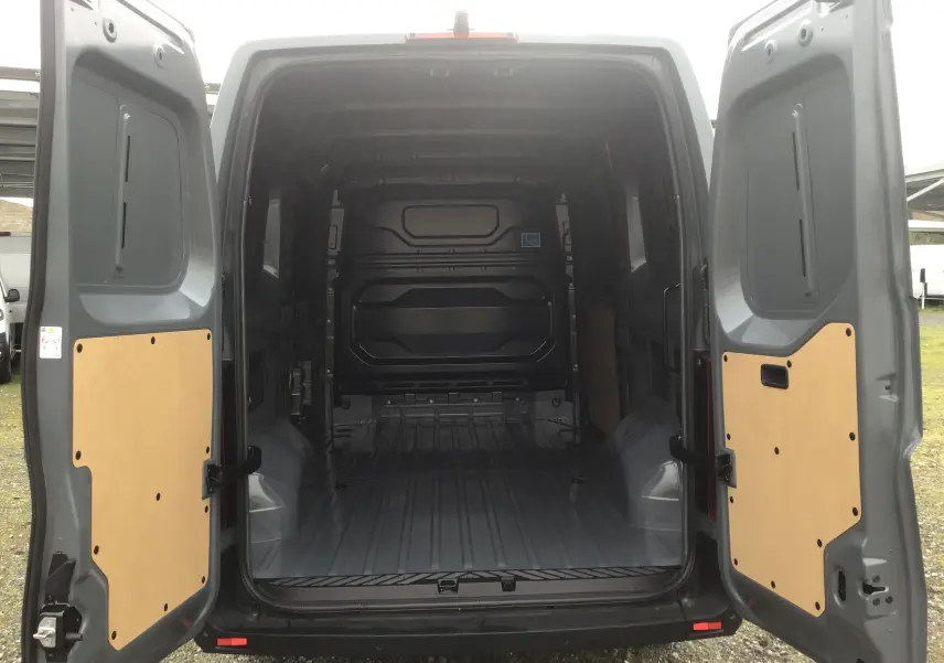 Vue arrière ouverte du Renault Master gris urbain 2025, montrant l’espace de chargement vide avec panneaux bois sur portes.