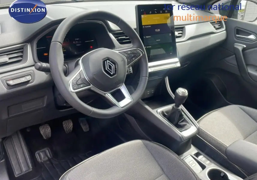 Vue intérieure côté conducteur du Renault Captur 2025, tableau de bord gris noir avec écran tactile vertical et boîte manuelle.