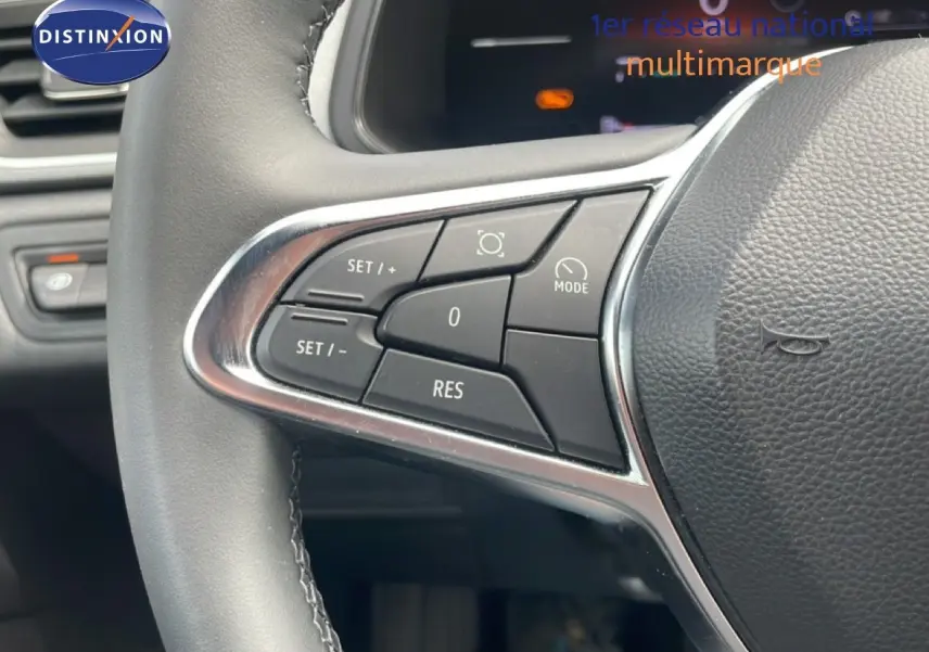 Gros plan sur les commandes gauche du volant en cuir noir du Renault Captur 2025, avec boutons de régulateur de vitesse.