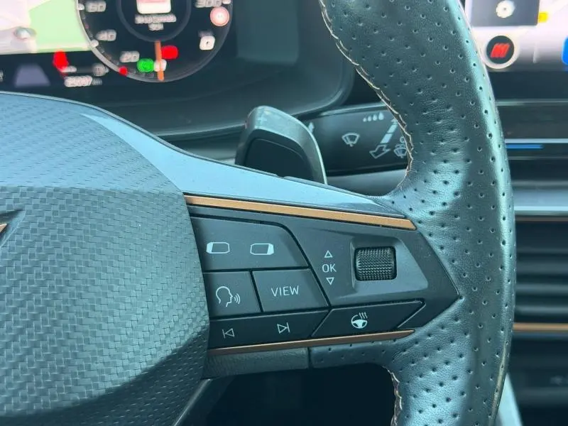 Gros plan sur le volant sport perforé noir du CUPRA Formentor 1.4 e-HYBRID 2024 avec commandes multifonctions et insert cuivre.