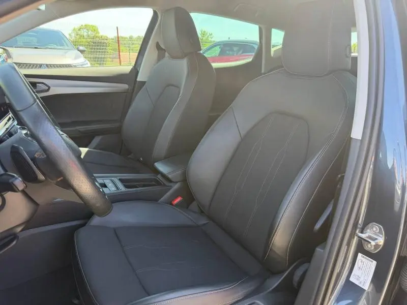 Vue intérieure côté conducteur du CUPRA Formentor 1.4 e-HYBRID 2024, sièges sport en tissu et similicuir noir, volant multifonction visible.