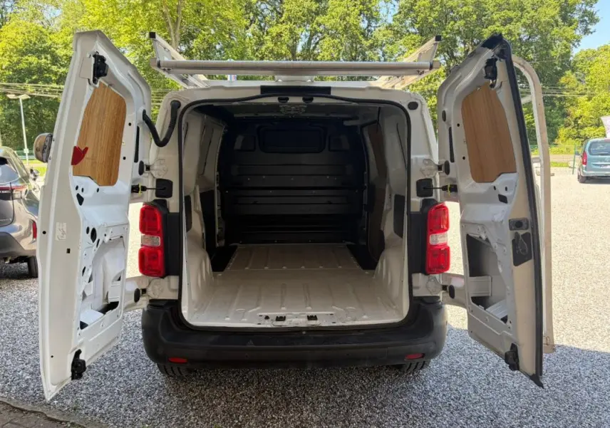 Vue arrière ouverte du Peugeot Expert Fourgon blanc L1H1 Confort 2019, montrant l’espace de chargement vide et la galerie sur le toit.