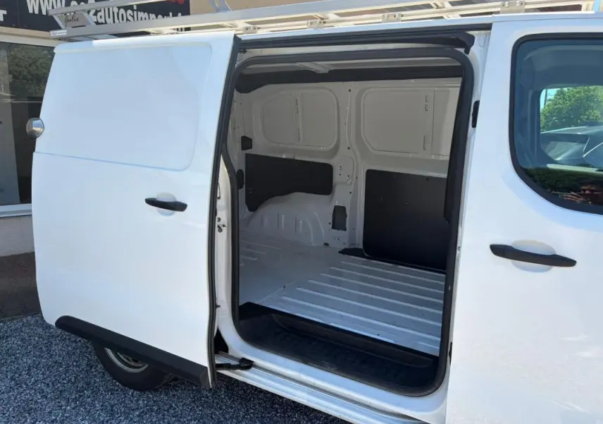 Vue latérale gauche d’un Peugeot Expert Fourgon blanc avec porte coulissante ouverte montrant l’espace de chargement vide.