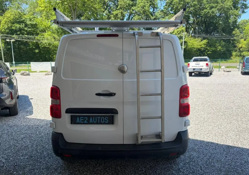 Vue arrière d’un Peugeot Expert Fourgon blanc avec galerie et échelle métallique fixée sur la porte droite.
