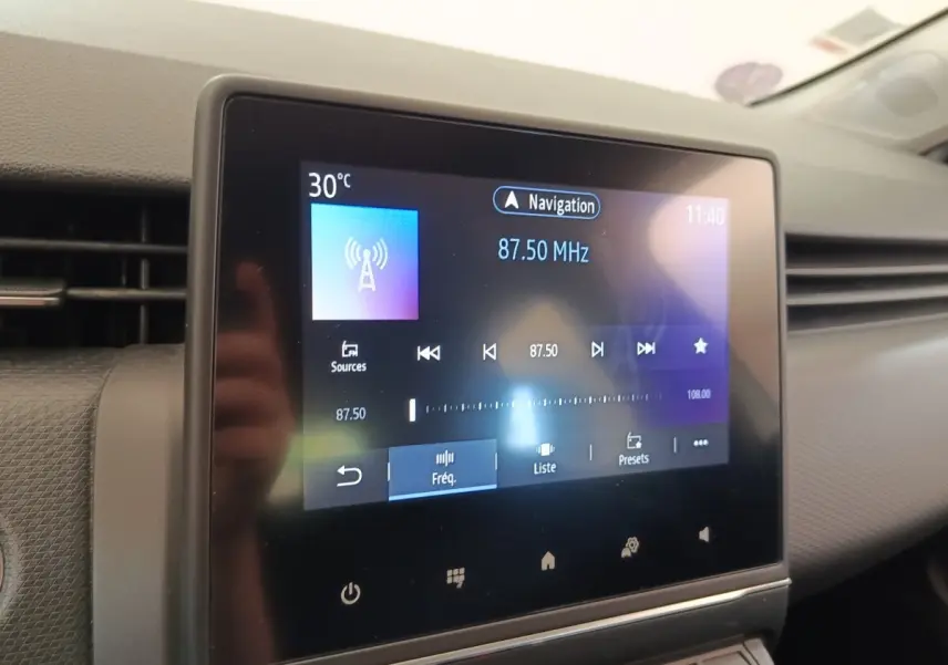 Écran tactile central de la Renault Clio Business gris clair, affichant la radio à 87,50 MHz en intérieur.