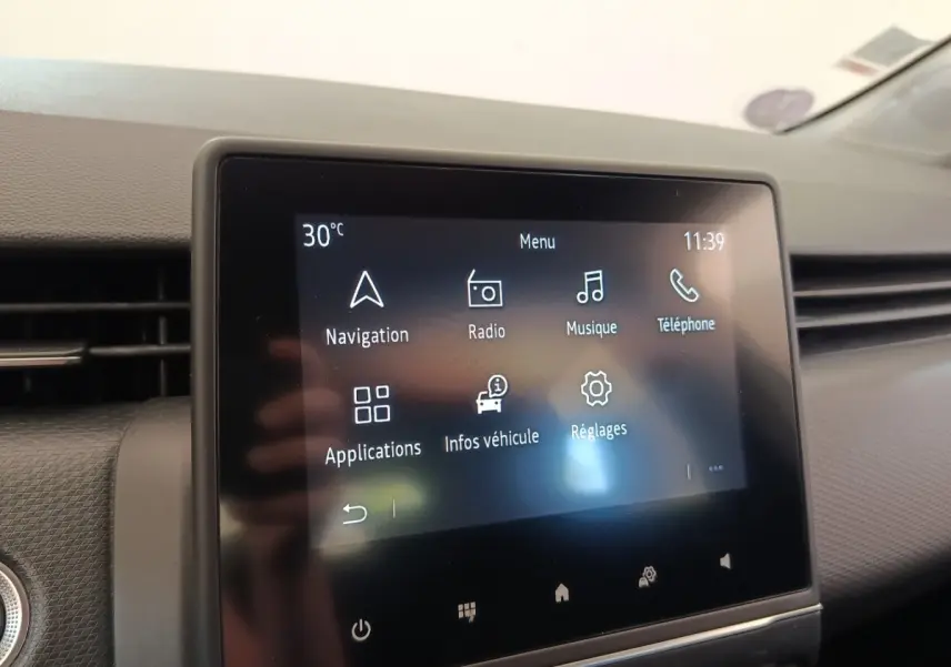 Écran tactile central de la Renault Clio Business gris clair, affichant le menu principal avec navigation et radio.