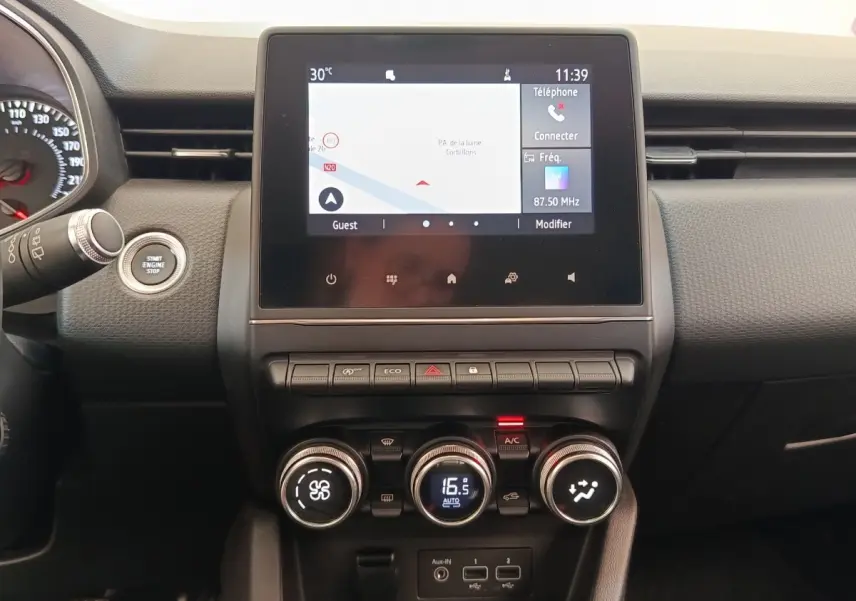 Vue rapprochée du tableau de bord de la Renault Clio Business TCe 100, écran tactile avec navigation et commandes de climatisation.