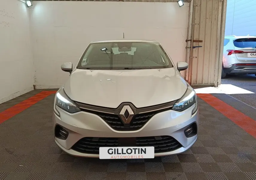 Vue avant d'une Renault Clio Business TCe 100 gris clair avec feux LED allumés dans un garage.