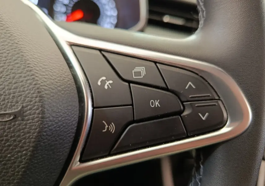 Gros plan sur les commandes multifonctions noires du volant cuir synthétique d’une Renault Clio Business gris clair.