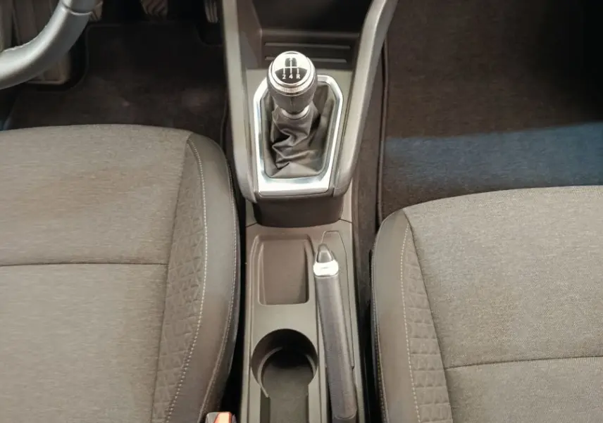 Vue intérieure centrée sur la console centrale d'une Renault Clio Business gris clair avec levier de vitesse manuel et sièges tissu noirs.