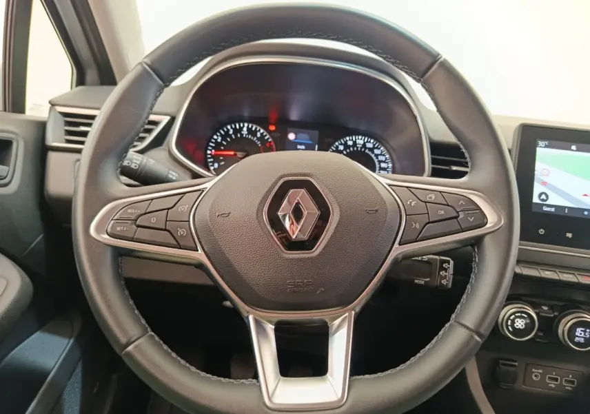 Vue rapprochée du volant cuir multifonctions de la Renault Clio Business TCe 100, avec tableau de bord et écran tactile visibles.