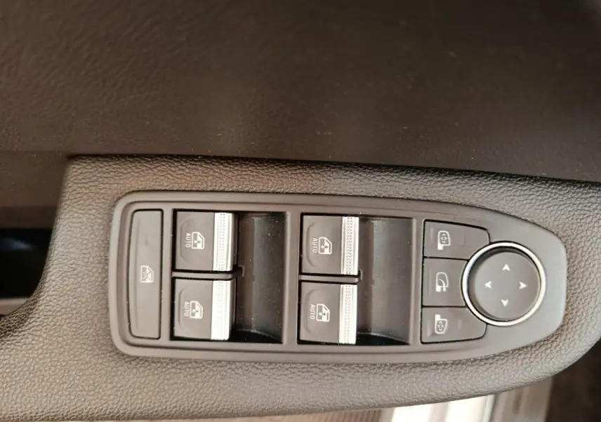 Gros plan sur les commandes des vitres électriques et rétroviseurs, intérieur noir de la Renault Clio Business TCe 100 2021.