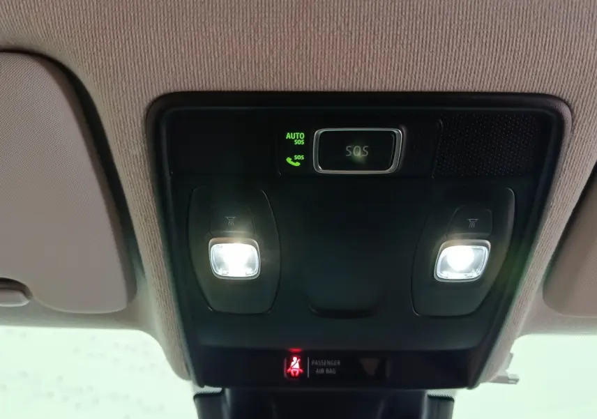 Vue intérieure en gros plan du plafonnier avec éclairages de lecture et bouton SOS allumé dans une Renault Clio gris clair.