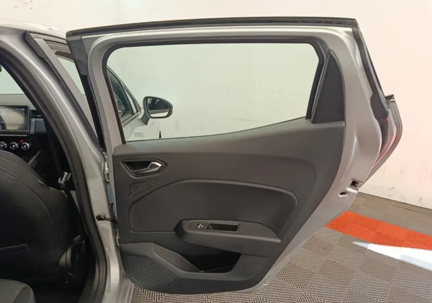 Vue intérieure de la porte arrière droite ouverte d'une Renault Clio gris clair, avec garniture noire et commande de vitre.