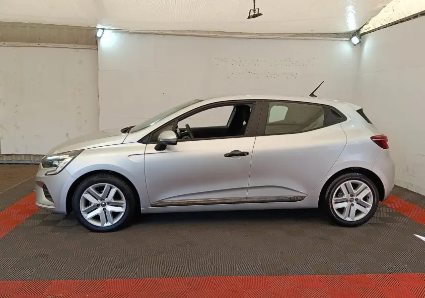Renault Clio Business TCe 100 gris clair vue de profil côté gauche dans un espace intérieur éclairé.