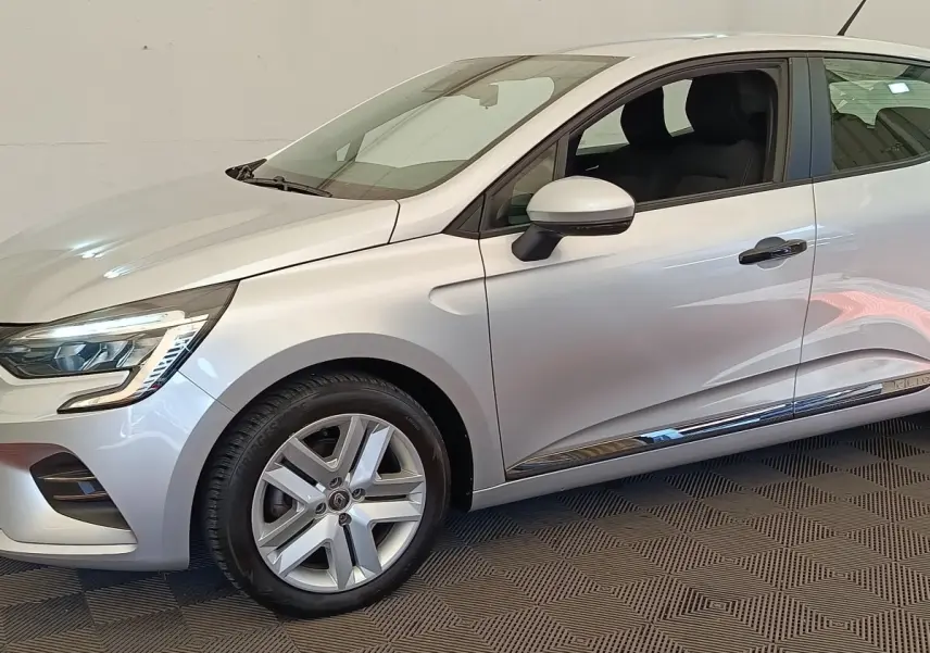 Vue de profil côté gauche d'une Renault Clio Business TCe 100 gris clair avec jantes alliage et feux LED avant visibles.