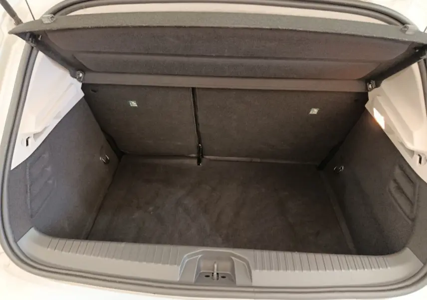 Coffre ouvert vu de l'arrière d'une Renault Clio gris clair, montrant un espace de rangement propre et vide.