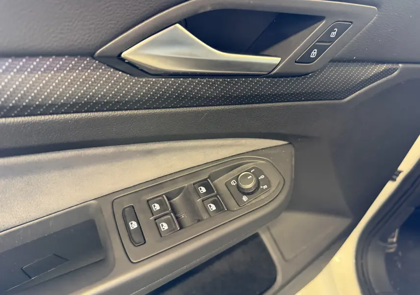 Gros plan sur la porte avant gauche de la Volkswagen Golf blanche 2023, montrant les commandes de vitres et de rétroviseurs.