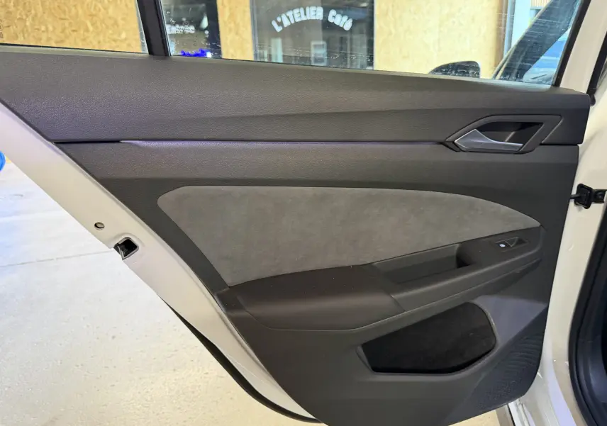 Vue intérieure de la porte arrière droite blanche d'une Volkswagen Golf 2.0 TDI 150 DSG7 R-Line avec garniture noire et grise.