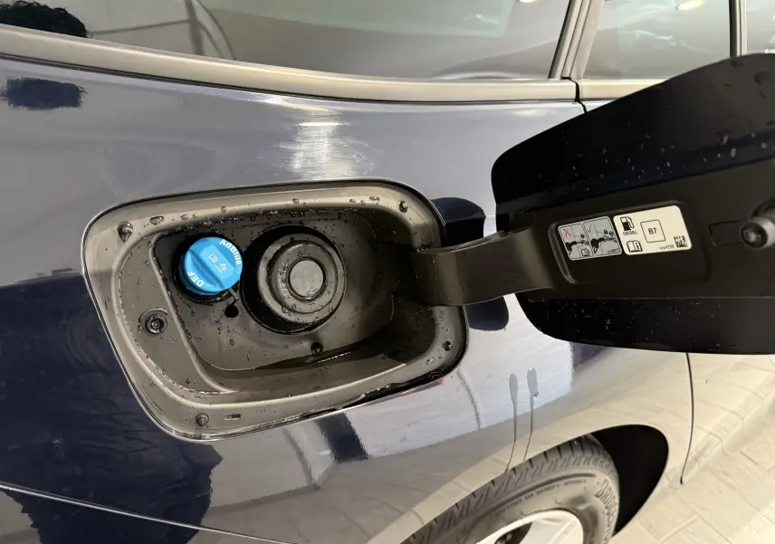 Gros plan sur la trappe à carburant côté gauche d'une Opel Insignia Sports Tourer bleu lune marine, avec bouchon AdBlue visible.