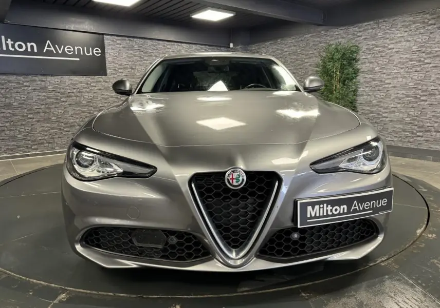 Vue frontale d'une Alfa Romeo Giulia gris métallisé avec calandre emblématique en V et phares LED distinctifs.