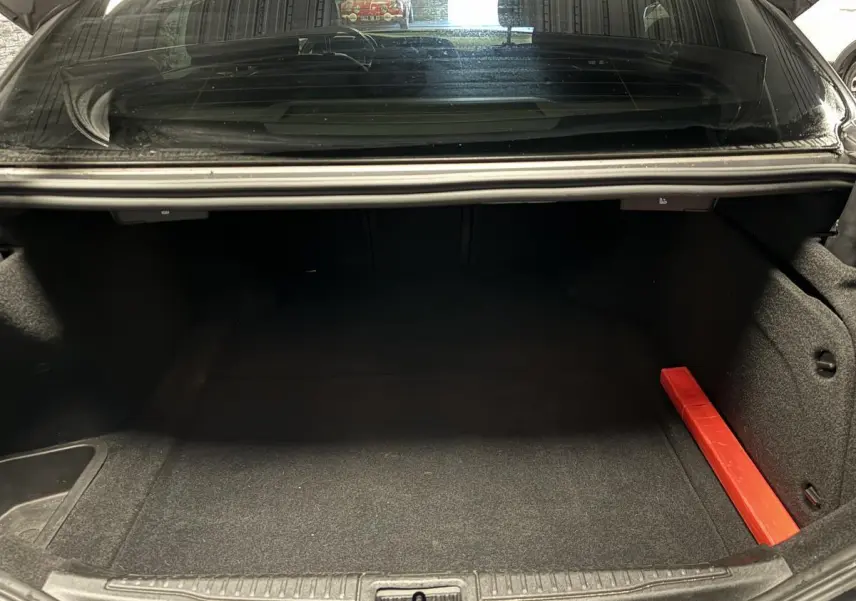 Coffre ouvert d'une Alfa Romeo Giulia gris 2021, montrant un espace de chargement vide avec un triangle de signalisation rouge.