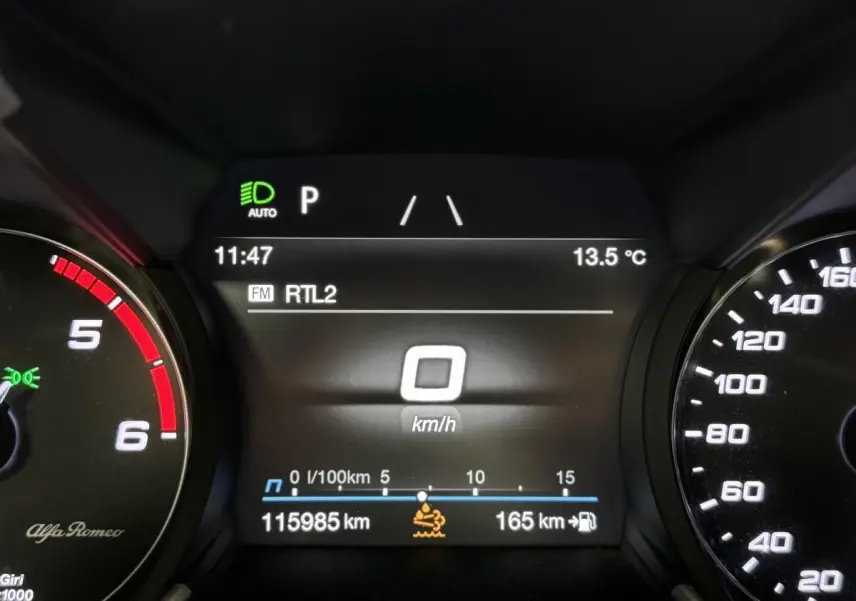 Tableau de bord numérique de l'Alfa Romeo Giulia gris, affichant 0 km/h et 115985 km au compteur.