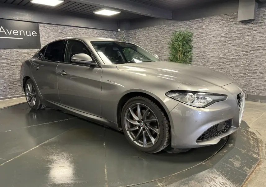 Alfa Romeo Giulia gris métallisé vue 3/4 avant droit avec jantes alliage 18 pouces Aero Scuro et vitres arrière surteintées.