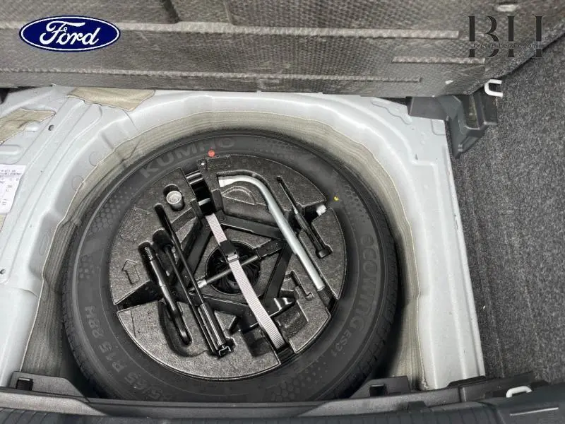 Gros plan sur la roue de secours et les outils de bord dans le coffre d'une Volkswagen Polo blanche.