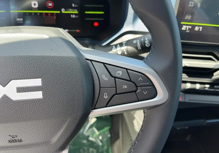 Gros plan sur le volant cuir à commandes multifonctions du DACIA Bigster 2025, avec tableau de bord numérique en arrière-plan.