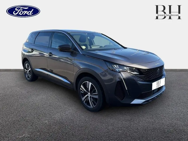 Peugeot 5008 gris Platinium vue 3/4 avant droit, calandre noire et jantes alliage distinctives.