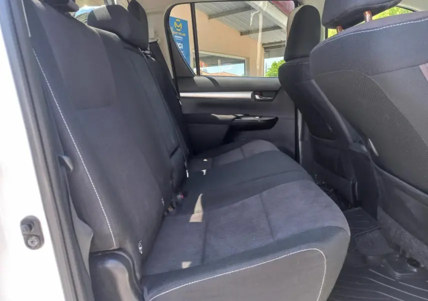 Vue intérieure côté gauche des sièges arrière en tissu noir du Toyota Hilux blanc double cabine de 2018.