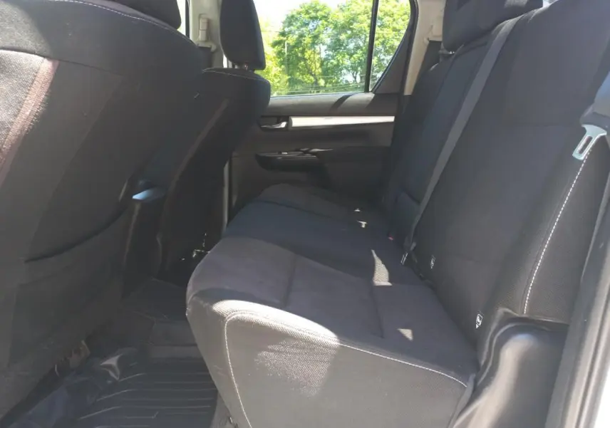 Vue intérieure côté droit sur la banquette arrière noire du Toyota Hilux 4x4 double cabine, avec ceinture de sécurité visible.