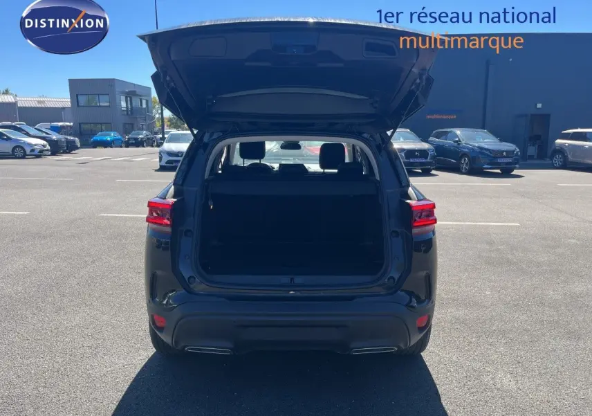 Vue arrière d'un Citroën C5 Aircross noir métal 2025 avec coffre ouvert sur parking extérieur.