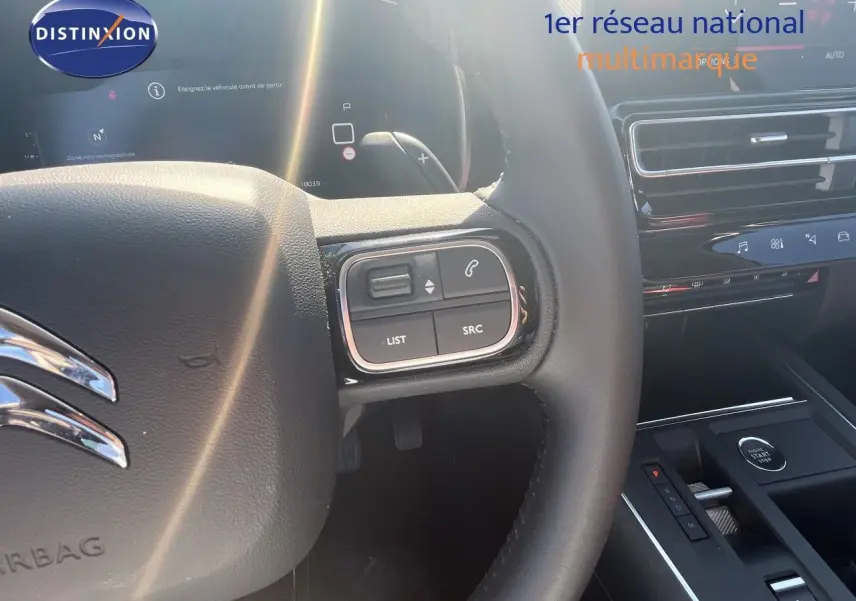 Vue intérieure centrée sur le volant noir du Citroën C5 Aircross 2025 avec commandes intégrées et tableau de bord moderne.