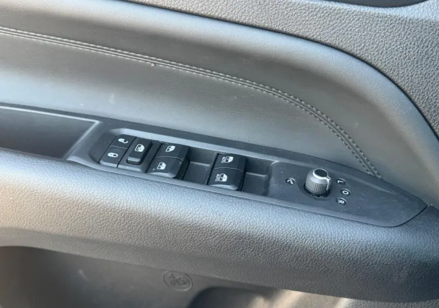 Gros plan sur la commande des vitres et rétroviseurs côté conducteur du Jeep Compass 2025, intérieur noir.