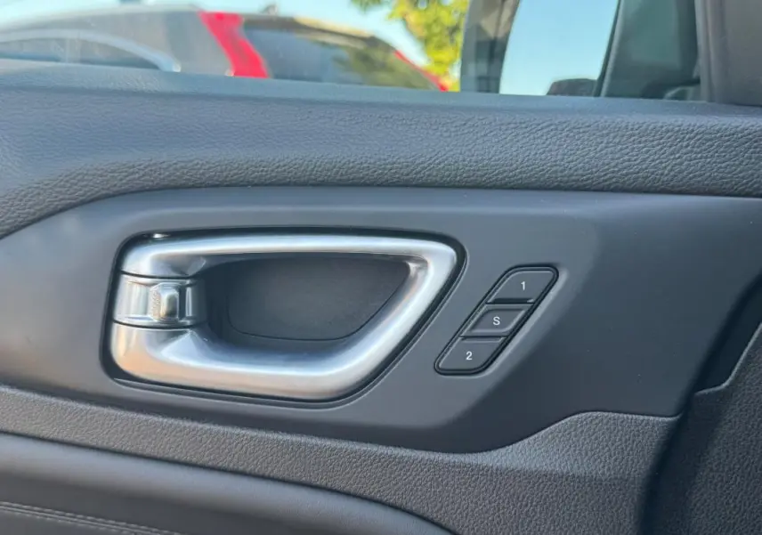 Poignée intérieure côté gauche en métal brossé avec boutons de mémorisation des sièges sur Jeep Compass bleu 2025.