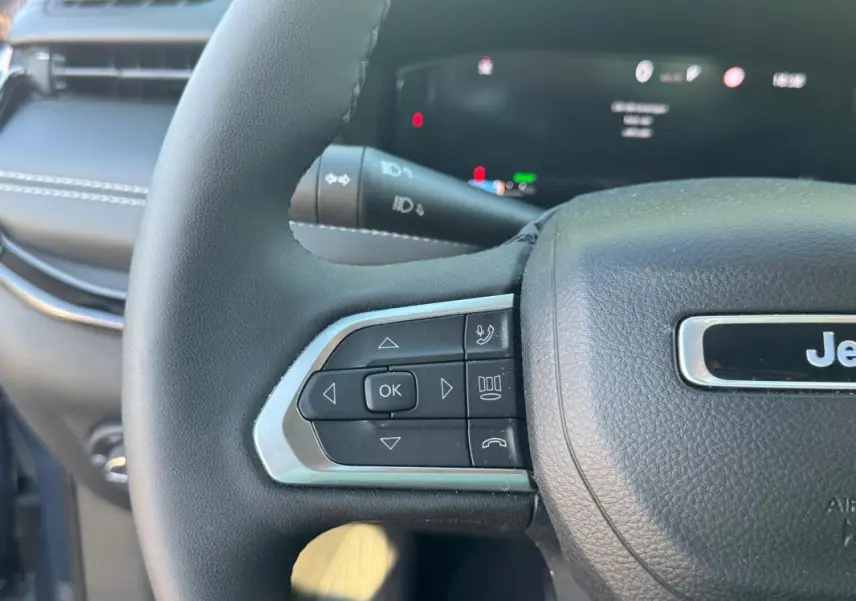 Gros plan sur le volant noir du Jeep Compass 2025 avec commandes intégrées et logo Jeep visible.