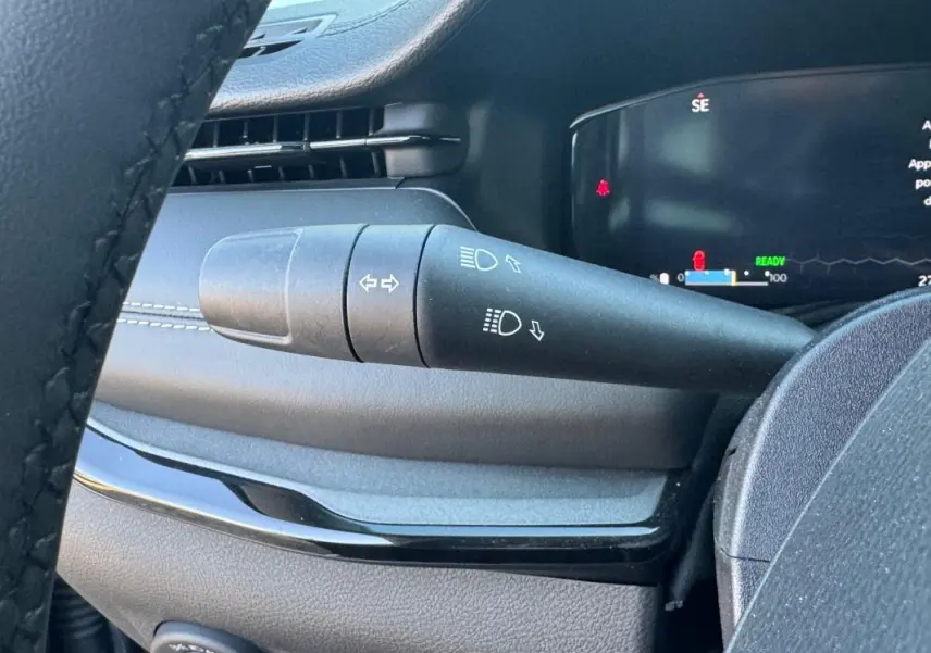 Gros plan sur la commande des phares et clignotants à gauche du volant dans l'habitacle du Jeep Compass 2025.