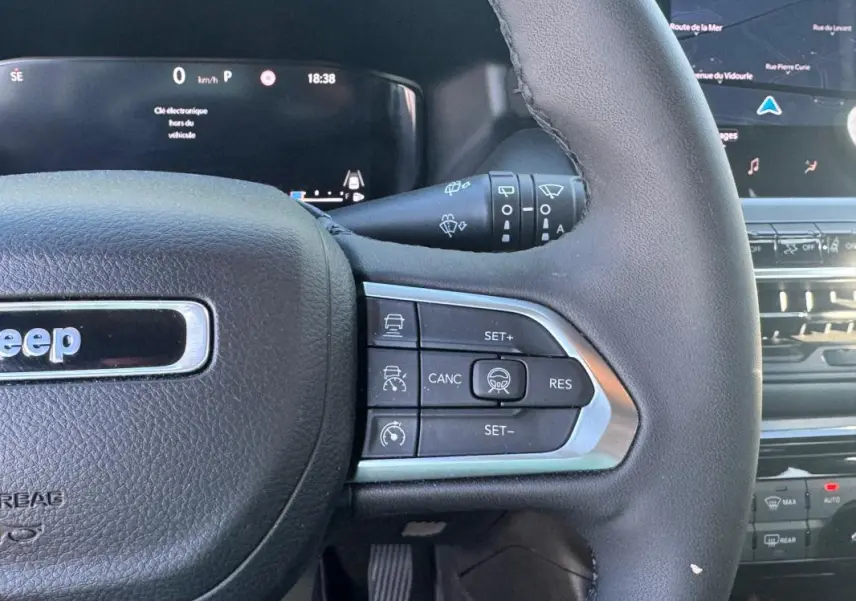Gros plan sur le volant côté droit du Jeep Compass bleu 2025 avec commandes de régulateur de vitesse et tableau de bord digital.