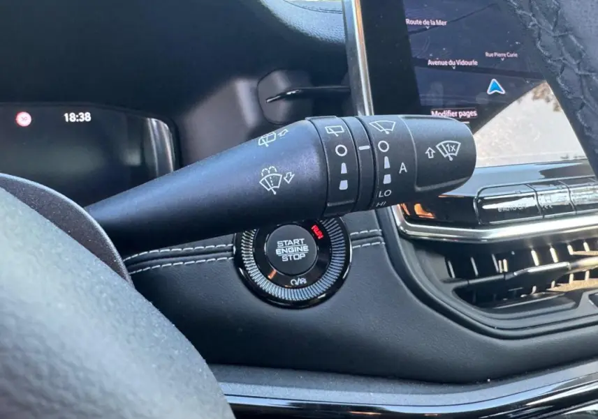 Gros plan intérieur sur la commande des essuie-glaces et le bouton start/stop du Jeep Compass bleu 2025, avec écran tactile visible.