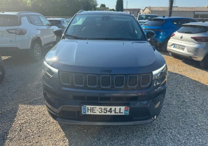 Vue avant d'un Jeep Compass bleu 2025 avec calandre distinctive et barres de toit visibles en extérieur.
