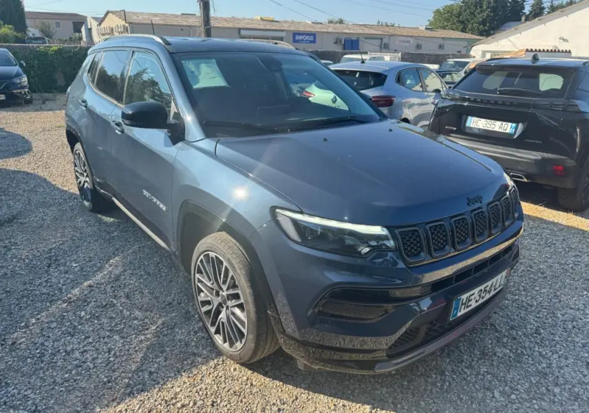 Jeep Compass bleu en 3/4 avant droit, avec jantes alliage 19 pouces et barres de toit visibles.