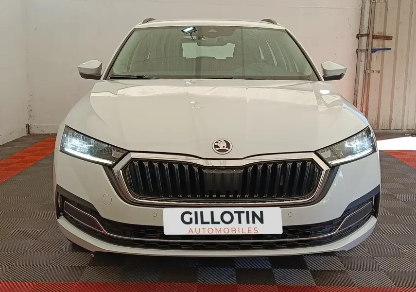 Vue frontale d'une Skoda Octavia blanche 2023 avec phares LED allumés et calandre noire distinctive.