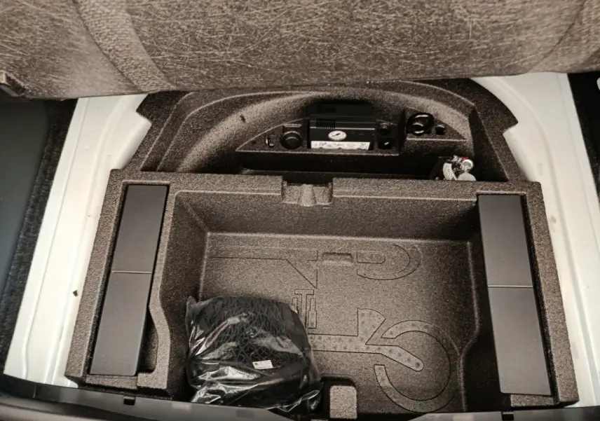 Coffre ouvert d’une Skoda Octavia blanche, vue de dessus sur le rangement sous plancher avec accessoires intégrés.