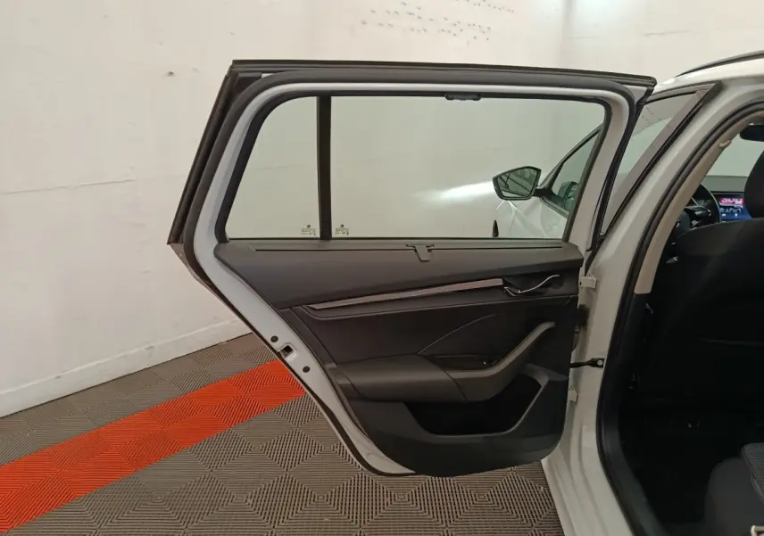 Porte arrière gauche ouverte d'une Skoda Octavia blanche, intérieur noir avec détails modernes et vitre teintée.