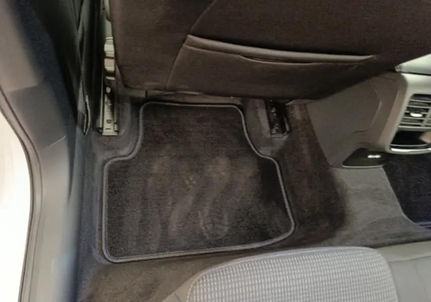 Vue intérieure du plancher arrière côté droit d'une Skoda Octavia blanche avec tapis de sol noir et siège gris.